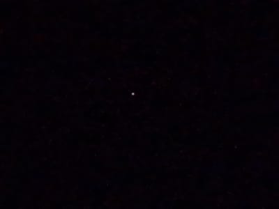 The image is a photograph of the night sky. A single, small, bright circular object, likely a celestial body such as the moon or a planet, is visible in the center of the dark frame. The background is uniformly black, indicating a lack of light pollution and a clear night. There are no discernible landmarks or contextual elements that would allow for the identification of a specific location in the city of Свіслацкі сельскі Савет, Belarus. The image is devoid of any human presence, objects, or actions.