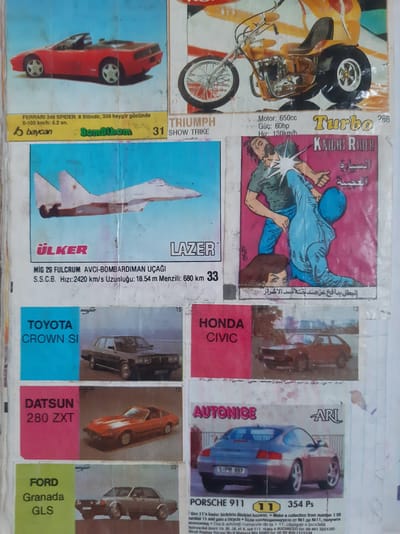 The image is a collage of various printed advertisements and images, possibly from a magazine or a collection of trading cards. The layout is dense, with multiple distinct sections featuring different products and themes.
In the top left, a red convertible sports car, identified as a "FERRARI 348 SPIDER," is depicted. Below it, text indicates "baycan" and "BomBibom" with the number "31" and "SHOW TRIKE."
To the right of the Ferrari, an image of a yellow three-wheeled motorcycle, a "TRIUMPH," is shown. Text beneath it reads "Motor: 650cc Güc: 60hp Hız: 130km/h" and "Turbo 286." Further to the right is a stylized logo that appears to say "KNIGHT RIDER" in English, with Arabic script underneath. An illustration depicts two figures in a struggle, one in blue and one in green, with a woman's head visible near the bottom.
Below the Ferrari, a white military jet, identified as "MiG 29 FULCRUM AVCI-BOMBARDIMAN UÇAĞI," is shown. The text below it states "S.S.C.B. Hızı: 2420 km/s Uzunluğu: 18.54 m Menzili: 680 km 33." Brands "ÜLKER" and "LAZER" are also visible.
To the right of the MiG, a black sedan, labeled "TOYOTA CROWN SI," is pictured. Above it is the word "mayfair" and the number "15."
Below the Toyota, a red sports car, a "DATSUN 280 ZXT," is featured. The text "DATSUN 280 ZXT" is on a pink background.
To the right of the Datsun, a darker red hatchback car, identified as "HONDA CIVIC," is displayed. The number "13" is visible above it.
Below the Honda Civic, a silver Porsche 911 is pictured. Text beneath it reads "AUTONICE ARI," and on the license plate "S-PR 997." Further text in smaller print mentions "PORSCHE 911 11 354 Ps" and provides information in what appears to be Turkish and potentially other languages, including "Dacă adunați numerele de la 1 la 11, câștigați o bicicletă."
In the bottom left, a grey sedan, identified as "FORD Granada GLS," is shown. The text "FORD Granada GLS" is on a green background. The word "mayfair" and the number "20" are visible above it.
The image is a compilation of various advertisements and depictions of vehicles, suggesting a hobby or interest in cars and possibly model collecting. There is no identifiable context or visual information within the image that places it specifically in the city of Semey, Kazakhstan.