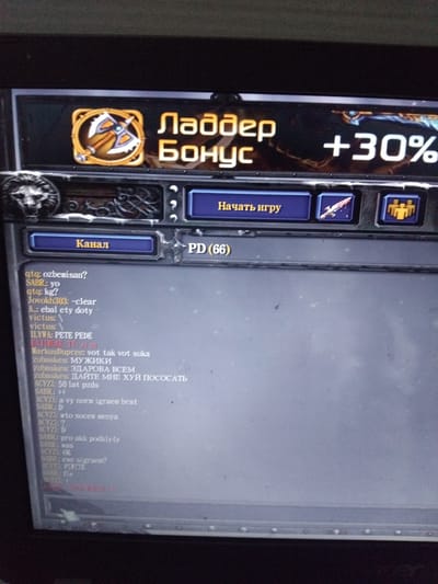 The image is a close-up shot of a screen, likely from a computer or mobile device, displaying what appears to be a game interface. The text on the screen is in Russian and other languages, including some English.
On the left side of the screen, there's a vertical bar labeled "Ладдер Бонус" (Ladder Bonus) with a +30% indicator. Below it is an icon resembling crossed axes. Next to this bar are buttons labeled "Начать игру" (Start Game) and "Канал" (Channel). There's also a label "PD (66)."
The right side of the screen features a chat window with various messages from different users. The messages are a mix of questions, statements, and potentially offensive language. Some usernames visible in the chat are "gtq," "SABR," "Jovokh303," "ILYWA," "zubaskes," "ACYZI," and "SABRE."
The image does not provide any information indicating a location in the city of Тоshkent, Uzbekistan, or about the city in general. It solely shows a screen display and chat messages from what seems to be an online game or platform.