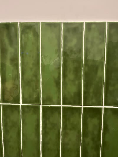 The image shows a wall tiled with dark green rectangular tiles, separated by thin white grout lines. The tiles are arranged in a grid pattern. The image was taken at coordinates 28.102 latitude, -15.415 longitude, which corresponds to a location in Las Palmas de Gran Canaria, Spain.