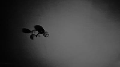 The image is a black and white photograph of a weather vane mounted on a wall. The weather vane is in the shape of a rooster and appears to be made of metal. It is positioned in the upper left quadrant of the image, against a plain, light-colored background. The lighting suggests it is daytime, possibly with some shadowing from the sun. The overall impression is one of simplicity and a focus on the weather vane itself. It is not possible to determine the specific location within Ialoveni, Moldova from the image.