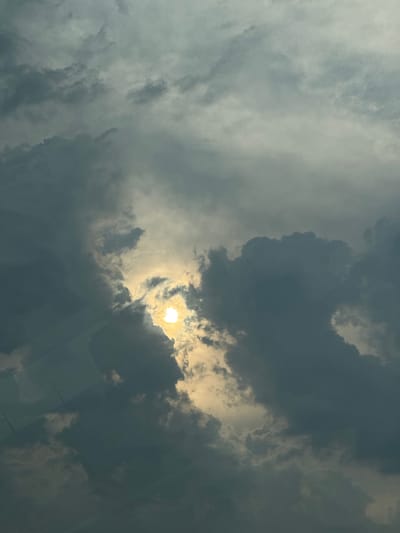 The media file is a photograph of a dramatic sky filled with clouds, with the sun partially visible behind them. The sun appears as a bright, glowing orb, casting a warm light through the darker storm clouds. The clouds themselves are a mix of dark, heavy masses and lighter, wispy formations, suggesting a dynamic and potentially changing weather pattern. The overall impression is one of a powerful and awe-inspiring natural display. There are no people or man-made objects clearly visible in the image, and no text is present. The scene is solely focused on the sky and the interplay of light and shadow within the clouds. Given the location context of Brashlen, Bulgaria, the image captures a moment of atmospheric beauty over that region. The time of day is suggested by the presence of the sun, though the specific time is not discernible. The weather is clearly cloudy, with indications of potential rain or storms due to the dark cloud formations.