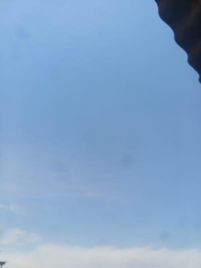 The image shows a clear blue sky with a dark, wavy object in the upper right corner. There are a few faint smudges or spots in the sky, and some wispy clouds at the bottom. There is no indication of the city of Jumashuy, Uzbekistan in the image.