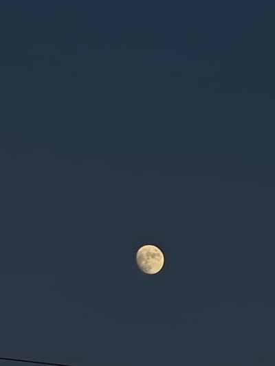 A full moon appears against a dark blue sky. A dark, thin line is visible in the lower right corner of the image, likely a power line. The scene appears to be taken at night. The specific location in Popasne, Ukraine, cannot be determined from the image. There are no people or interactions visible.