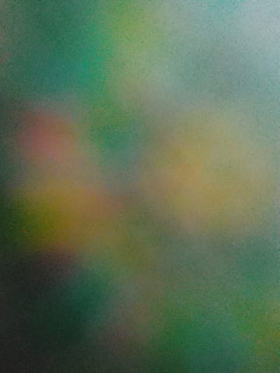 This image is an abstract, impressionistic composition dominated by muted greens, blues, and earthy tones. There are no discernible subjects like people, objects, or a clear scene. The textures appear grainy, suggesting it might be a photograph with a filter or a painting. The blend of colors evokes a naturalistic, possibly atmospheric, feel, perhaps reminiscent of a landscape or a cloudy sky. There are no identifiable location cues, time of day indicators, or emotional expressions. No text is visible in the image.