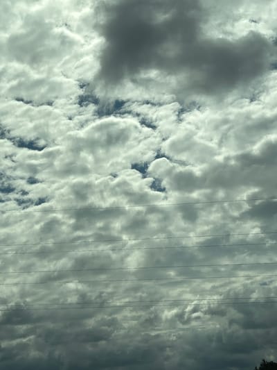 The image shows a cloudy sky with visible power lines stretching horizontally across the frame. The clouds are a mix of dark grey and bright white, suggesting a dynamic weather system. The power lines are dark and appear to be suspended in the air. The overall impression is of an overcast day. The image does not contain any people or specific landmarks that would indicate its location in the city of Малевіцкі сельскі Савет, Belarus.