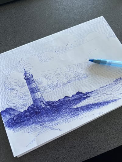 A pen drawing on paper depicts a lighthouse on a rocky shore with turbulent waves. The lighthouse is tall and striped, leaning slightly to the left. The sky is filled with swirling clouds, and two birds are visible in the distance. A blue pen is placed on the paper, pointing towards the drawing. The drawing is placed on a dark, textured surface, possibly a desk. The scene does not contain any elements that would suggest a specific location within the city of Rezina, Moldova.