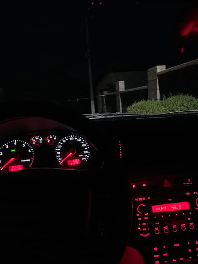 The image shows the interior of a car at night, with the dashboard illuminated by red light. The driver's perspective reveals the speedometer, tachometer, fuel gauge, and temperature gauge. The digital display shows the time as 22:08 and the date as 18.06.2025. The odometer reads 273751, with the speedometer indicating a speed between 0 and 10 km/h. The radio is on and tuned to FM 93.3. Outside the car, a street light and some greenery are visible. The location is not specified as Ponebel, Ukraine, nor is there any information to confirm this.
