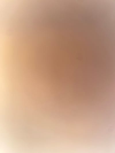 The image is a blurred, abstract photograph with a gradient of warm colors, ranging from light beige on the left to a muted reddish-brown on the right. There are several small, dark specks scattered across the surface. The lighting appears soft and diffused, creating a hazy effect. There are no discernible objects, people, or actions depicted in the image. The location in Ablanitsa, Bulgaria, is not visually represented.
