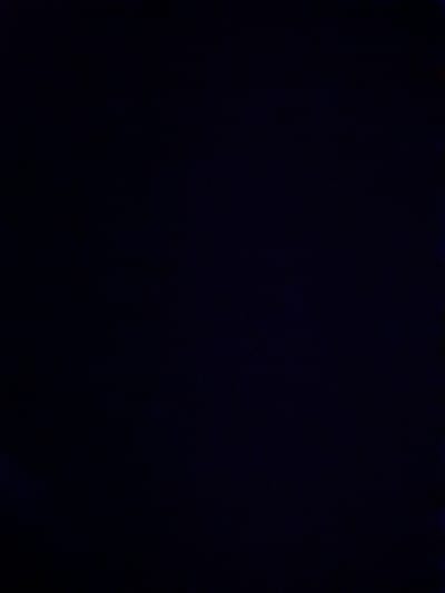 This is a dark, grainy, and blurry image. The overall scene is very dark, making it difficult to discern specific subjects or activities. There are some faint, almost imperceptible lights or reflections visible at the very top and bottom edges of the image, which appear to be a very faint blue and red respectively. The rest of the image is a deep, uniform dark blue or black. It is not possible to identify any people, objects, specific activities, time of day, weather, location cues, or emotions. There is no visible text. The image appears to be taken in a low-light environment, possibly at night or in a very dark interior. The low quality and darkness obscure any potential details, rendering the scene abstract.