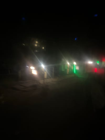 The image depicts a dark, out-of-focus scene, possibly at night, with several blurred lights. There are bright white lights that appear to be headlights of a vehicle, and some colored lights, including green and red. The environment seems to be an outdoor area, possibly a street or a road in a town or city. The blurriness of the image suggests it might have been taken while moving, such as from a vehicle. There are no clearly identifiable people or specific structures. The overall impression is that of a low-light, possibly urban, environment. The specific location in Richky, Ukraine cannot be determined from the visual information alone.
