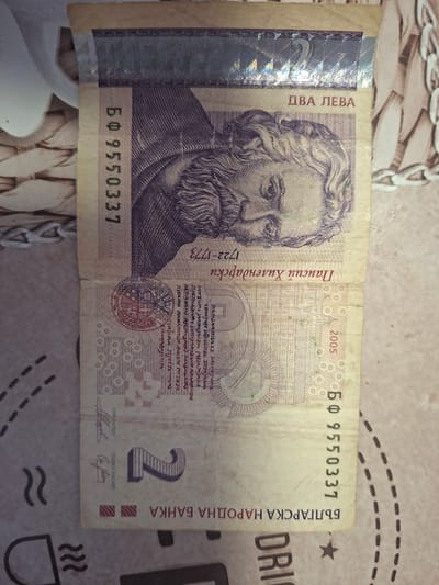 The image shows a Bulgarian two leva banknote on a patterned surface. The note features a portrait of Paisius of Hilendar and the date 2005. The serial number is БФ 9550337, printed twice on the note. The text on the banknote is in Bulgarian Cyrillic. The Bulgarian National Bank is named on the note. There are no specific details in the image or provided in the OCR text that suggest a connection to the city of Radomir, Bulgaria.
