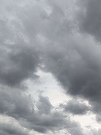 A cloudy sky is depicted in this vertical, medium-shot photograph. The clouds are predominantly dark gray, with some lighter patches indicating breaks in the overcast. The scene appears to be an outdoor environment, likely a view of the sky from ground level. No people, objects, or specific landmarks are visible, suggesting a focus on the atmospheric conditions. The image lacks any contextual clues to pinpoint a specific location within the city of Skurygino, Russia, or any identifiable activity.