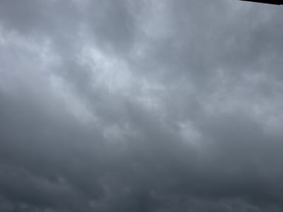 The image shows an overcast sky with thick, dark clouds. The sky is gray and appears to be either pre-storm or post-storm. There are no discernible features or objects within the frame, such as buildings, people, or any other elements that would suggest a specific location within the city of Otradny, Russia, or any other city. The image is a close-up of the sky, and the top edge of the frame has a dark, horizontal line that could be the edge of a roof or some other structure, but it is not clearly identifiable.