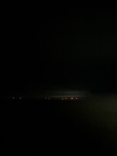 The image is a nighttime photograph of a dark, possibly foggy or misty, environment with a faint horizontal line of red lights visible in the distance. The lights appear to be spaced out and are the only significant light sources in the frame. The foreground is completely dark. There is no visible indication of the city of Gorun, Bulgaria within the image itself.