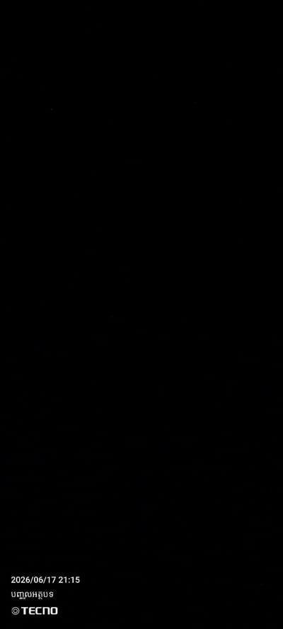 This media file is an image that appears to be a screenshot or a photograph with a watermark. The background is entirely black, indicating it could be a photo taken in low light conditions, or it is a digital image with a deliberately dark aesthetic.

In the bottom left corner of the image, there is visible text. The first line reads "2026/06/17 21:15", indicating a date and time. Below this, there is text in what appears to be Khmer script, which translates to "TECNO". The "TECNO" logo is also present, enclosed in a circle with a copyright symbol. This suggests that the image was taken or processed using a TECNO device.

Due to the black background and the limited visible elements, there are no discernible subjects like people or objects, nor is there information about the scene, setting, activity, time of day, weather, or location cues, other than what is provided by the timestamp and the brand watermark. No specific emotions can be inferred from the image itself.