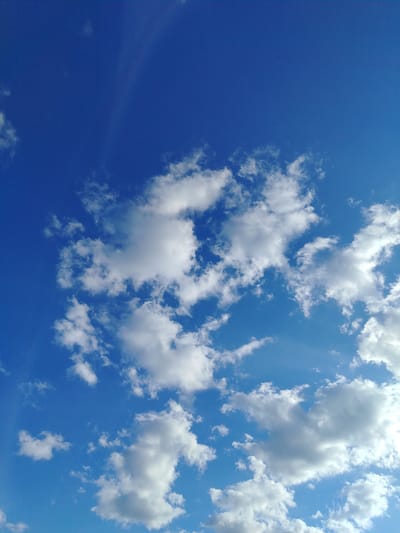This media file is a photograph of a bright blue sky with scattered white clouds. The clouds vary in size and density, with some appearing fluffy and others more wispy. The sky is clear and appears to be a sunny day. There are no people or objects visible in the frame, and no text is present. The overall scene evokes a feeling of openness and a pleasant, clear day. The lighting suggests it is daytime, likely mid-morning or afternoon given the brightness of the sky. The location is identified as Zyryanskoye, Russia, but no specific landmarks or environmental cues within the image itself confirm this.