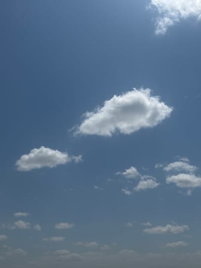 The image shows a clear blue sky with scattered white clouds. There are no people, animals, buildings, or other objects visible in the frame, except for the clouds themselves. The scene depicts a daytime sky, likely outdoors, with good visibility. The clouds are varied in size and shape, with some appearing fluffy and others more wispy. There is no indication of any specific location within село Умбеталы Карибаева, Kazakhstan.