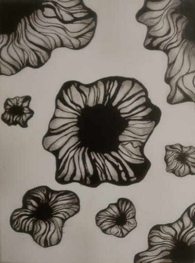 This is a black and white drawing featuring abstract, organic shapes that resemble flowers or fungi. The shapes have a central dark core with radiating, wavy lines that create a sense of texture and depth. Some of the shapes are large and prominent, taking up a significant portion of the frame, while others are smaller and scattered across the background. The drawing style is sketchy and dynamic, with varying line weights and shading. There is no indication of people, a specific scene, or any event taking place. The background is plain white, suggesting a studio or indoor setting. There is no visible text in the image. The overall impression is one of abstract, natural forms rendered in a bold, graphic style.