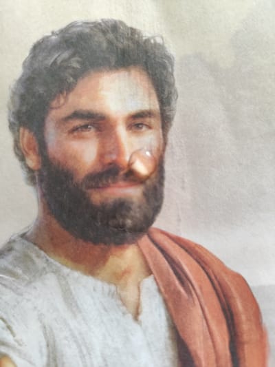 The image shows a close-up portrait of a man. He has short, dark hair, a full beard, and a light complexion. He is wearing a white tunic with a red garment draped over his shoulder. He is looking directly at the viewer, with a slightly serious expression. The image is a painting. The coordinates provided, 45.788 latitude and 3.11 longitude, correspond to the city of Clermont-Ferrand, France. However, the image does not depict anything specific to the location. It's impossible to tell where or when this image was taken. It is just a portrait of a man.