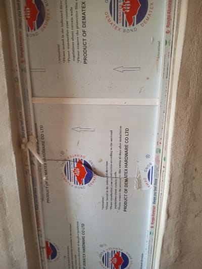 The image shows a construction material with the brand "DEMATEX BOND" and "Rongtai Aluminum." It features the company name "DEMATEX HARDWARE CO LTD" and instructions: "Please install in the indicated direction," "Please standardize your construction according to the national regulations about curtain walls," and "Please remove the protective film within 45 days after installation." The phrase "Always your best choice" is also present. The material appears to be attached to a wall.