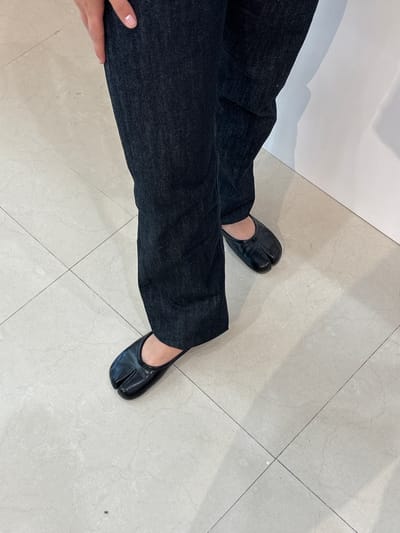 A person wearing dark jeans and black split-toe shoes stands on a light-colored tiled floor. The person's hand is visible near the bottom left corner of the image. The scene appears to be indoors. The location is not San Francisco Ocotlán (Ocotlán), Mexico.