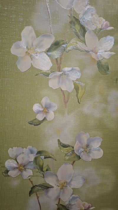 The image is a close-up, vertical, eye-level shot of a painting of white apple blossoms on a textured, pale green background. The painting features several clusters of blossoms and leaves. The blossoms are detailed with delicate petals and yellow centers. The leaves are green and somewhat glossy. The background has a subtle, horizontal texture, possibly mimicking canvas or linen. The lighting appears to be soft and diffused, with some areas of the painting having a slight sheen, indicating highlights. The painting is a still life and does not depict any specific location within the city of Navoiy City, Uzbekistan, or any people or actions.
