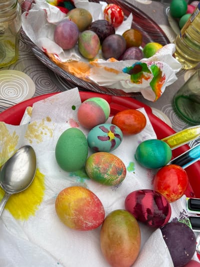The image shows dyed Easter eggs resting on paper towels inside a tray and a bowl. A spoon is present, and food coloring is visible. The location is most likely a residence or a place associated with Easter celebrations, without specific identifying features related to Zlati Voyvoda, Bulgaria.