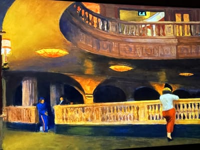 This painting depicts an interior scene within a grand architectural space in the city of Reus, Spain. The setting features a multi-level hall, likely a theater or opera house lobby, illuminated by warm, artificial light. The upper level includes a curved balcony with a dark railing and ornate balusters, behind which soft light emanates from an unseen area, revealing a small green exit sign. The lower level is dominated by a substantial, golden-yellow balustrade with intricate detailing. Behind this balustrade, several dark arched openings are visible, some glowing with warm light from within.

Three figures are present: On the far left, a person in a blue uniform with an orange stripe stands near a fluted column. To their right, a partially visible figure in dark attire is positioned behind a partition. On the right, a prominent figure with a white top, red pants, black shoes, and yellow hair or hat, leans forward over the lower balustrade, observing the space beyond. Ceiling-mounted, circular orange-yellow light fixtures provide primary illumination, creating strong contrasts between brightly lit surfaces and deep shadows throughout the ornate environment.