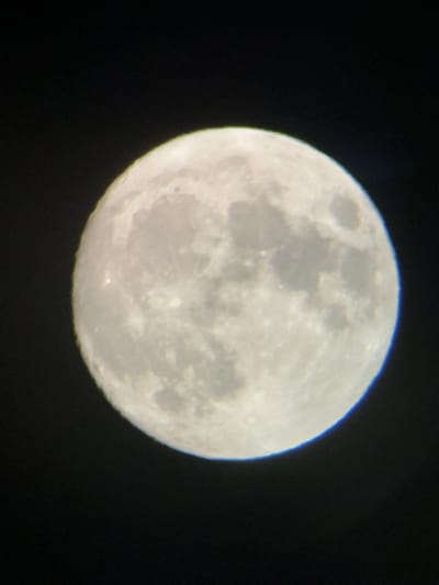 The image is a photograph of a full moon against a dark, starry sky. The moon is well-lit and its surface features, such as craters and maria (dark plains), are visible. There are no people, buildings, or any other elements indicative of a specific location on Earth, including Târgu Neamț, Romania, in the image. The photograph appears to be taken from a location with a clear view of the night sky, possibly using a telescope or a telephoto lens.
