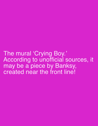 The image displays a solid magenta-colored background. White, sans-serif text is superimposed and centered in the lower portion of the frame. The text reads: "The mural 'Crying Boy.' According to unofficial sources, it may be a piece by Banksy, created near the front line!" There are no visual elements depicting a city, specific location, people, subjects, objects, actions, interactions, or an environment within the image. The image is purely a graphic composition of colored background and text; no visual representation of Izium, Ukraine, or any location within it, is present.