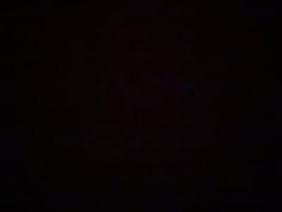 The image is a very dark, almost black, photograph with minimal visible detail. It appears to be an indoor setting, possibly a room, with some very faint texture visible on the surface, suggesting fabric or a textured wall. There are no discernible objects, people, or activities depicted. The extreme darkness makes it impossible to determine the specific location within Gorna Malina, Bulgaria, or any other identifying features of the environment.