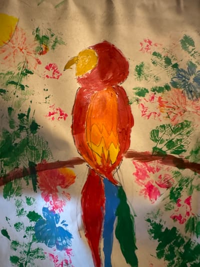 The image is a painting of a parrot perched on a branch, surrounded by floral and foliage designs. The parrot has a red head, a body with red, orange, and yellow sections, and a tail with red, blue, and green sections. The branch is brown. The background includes leaf and flower prints in various colors like green, blue, pink, and red. There is no information that allows me to know the location in Mèo Vạc Commune, Vietnam.
