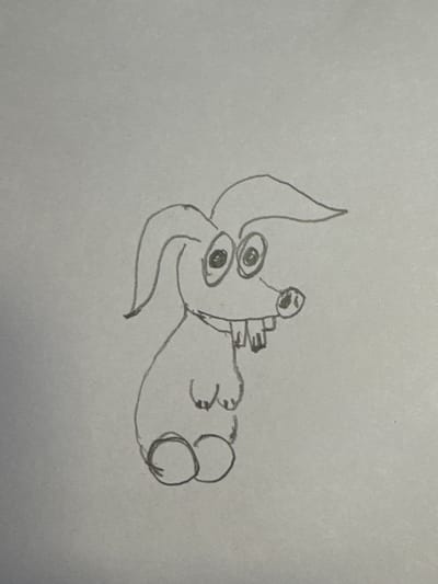 A crude pencil sketch depicts a cartoonish creature with long ears, large circular eyes with dark pupils, a small snout with nostrils, and prominent buck teeth. The creature has two small arms and two circular feet. The drawing is rendered on a plain, grey background. There is no indication of a location in Перовское сельское поселение, Ukraine.