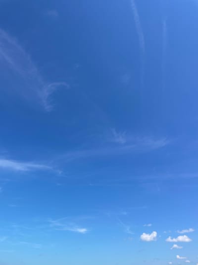 The media file depicts a bright blue sky with wispy clouds. The sun is high in the sky, suggesting it is daytime. There are faint contrails visible in the upper left portion of the image, indicating air traffic. In the right portion of the sky, there are small clusters of puffy white clouds. The overall impression is of a clear and pleasant day, likely in an outdoor setting. There is no visible text in the image.