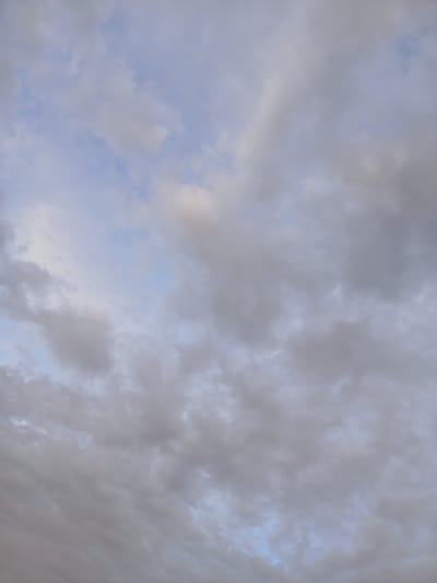 The image is an aerial view of a cloudy sky. The clouds are predominantly gray and white, with some patches of lighter blue sky visible. There are no discernible landmarks or structures from the city of Марьевка, Russia, visible in the frame. The image captures a natural atmospheric phenomenon.