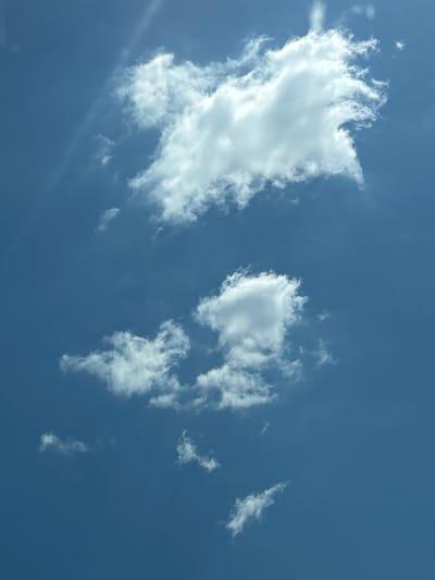The image depicts a bright blue sky with scattered white cumulus clouds. The clouds are varied in size and shape, with the largest cloud occupying the upper central portion of the frame. The sky is clear and sunny, suggesting fair weather. There are no people, buildings, or any other man-made objects visible in the frame. The image is a natural landscape photograph. It is impossible to determine the location in the city of Vakarel, Bulgaria from the provided image alone.