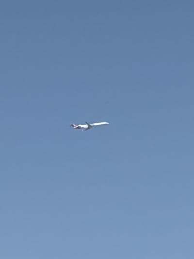 The image shows a person skydiving. The person is wearing a blue suit and a red helmet. The sky is clear and blue, indicating it is daytime. The background is a solid blue sky, with no visible land or other objects. The person appears to be falling through the air, with their arms and legs spread out. The image is taken from a low angle, looking up at the skydiver. It is not possible to determine the exact time of day, but it is likely daytime due to the bright sky. There are no visible text elements in the image.