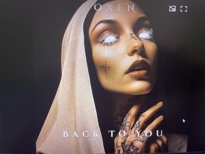 This is a close-up cover image of a woman wearing a beige headscarf that covers her hair and part of her face. Her eyes are wide open with bright white irises and dark pupils, giving her an intense and striking appearance. She has a cross tattoo on her cheek and further intricate tattoos on her hands and fingers. Her lips are painted with a deep red lipstick and are slightly parted.
The background is dark and moody. The text "OXEN" is visible at the top of the image, above the woman's forehead. Below her chin, the text "BACK TO YOU" is written in a lighter color.
The overall mood is dramatic and somewhat gothic, with the stark contrast between the woman's luminous eyes and the dark background. There are no cues about the time of day, weather, or specific location within Punta Ala, Italy. The image appears to be a album cover or promotional material.