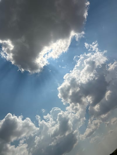 This media file is a photograph of a sky filled with clouds. The scene depicts a bright, sunny day with a mix of dark and light clouds. Rays of sunlight are visible, piercing through gaps in the clouds, creating a dramatic effect. The clouds are varied in texture and form, with some appearing wispy and light, while others are dense and shadowed.
The image conveys a sense of the natural beauty of the sky and the dynamic play of light and shadow. The weather appears to be partly cloudy, with the sun actively breaking through. There are no discernible objects or people in the frame, as the focus is solely on the sky. The time of day can be inferred to be daytime due to the strong sunlight and visible sun rays. No specific location cues are evident within the image itself, but the provided location context is Загорци, Bulgaria. The overall emotion conveyed by the image is one of awe at the power and beauty of nature. No visible text is present in the image.