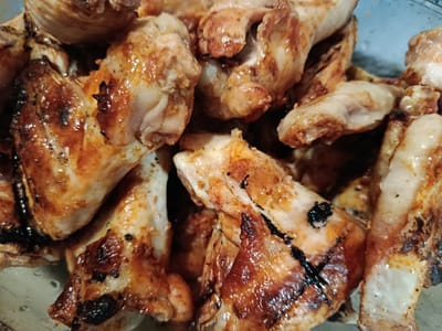 A close-up, overhead shot shows a pile of cooked chicken wings. The wings are golden brown with some charred edges and visible seasoning. They appear to be in a bowl or on a platter. The lighting suggests an indoor setting. There is no visible indication of the city of Niš, Serbia.