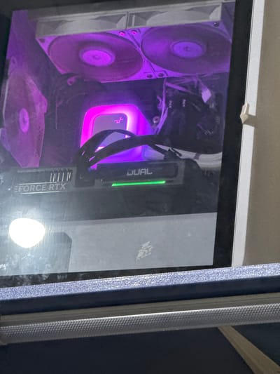 The image displays the interior of a computer tower, illuminated by purple and pink LED lighting. A graphics card, labeled "EFORCE RTX" and "DUAL", is visible. Above the graphics card are several fans. The computer appears to be in a room, with part of a blue and gray case visible in the foreground. There is no discernible information indicating the image was taken in Sotsialisticheskii, Russia.