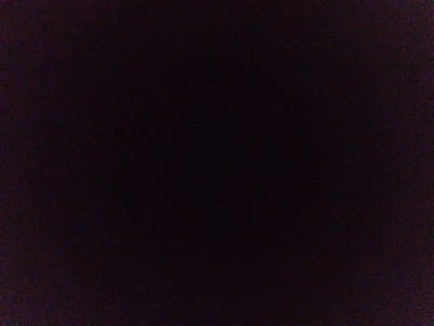 The image is a dark, grainy, and blurry photograph of what appears to be an outdoor scene. The overall darkness and lack of clear detail make it difficult to discern specific objects or people. There are hints of purple and red hues within the darkness, possibly indicating some form of artificial lighting or residual color from the environment. The image quality suggests it may have been taken in low light conditions or with a low-resolution camera. Without any discernible landmarks or identifying features, it is impossible to determine the location within the city of Iziaslav, Ukraine, or any specific details about the scene.