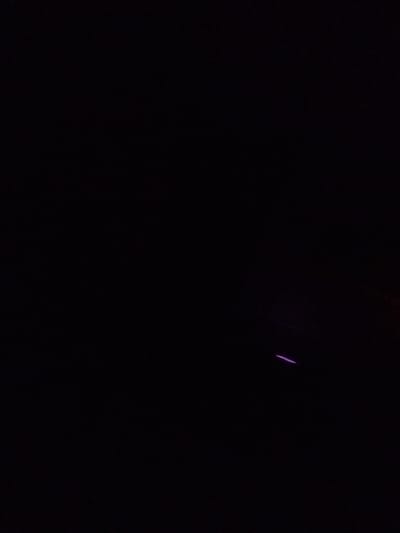 The image shows a dark, outdoor scene with a thin, angled purple line visible towards the bottom right. The background is almost entirely black, suggesting it is nighttime or a very dimly lit environment. No people or clear objects are discernible, apart from the faint purple light, which could be from a light source like a laser pointer or a distant illuminated sign. The overall impression is one of darkness and a lack of clear detail, with the purple line being the only distinct visual element. The given location context of Tula, Russia, does not provide specific visual cues within the image itself.