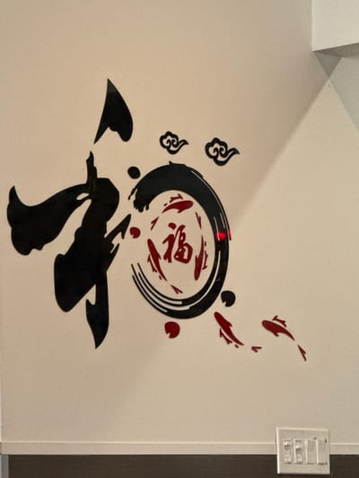 The image shows a wall in Darien, United States of America, adorned with black and red decorative wall stickers. These stickers depict Chinese-inspired artwork, including stylized fish, clouds, and abstract shapes. A light switch is visible near the right edge of the wall.