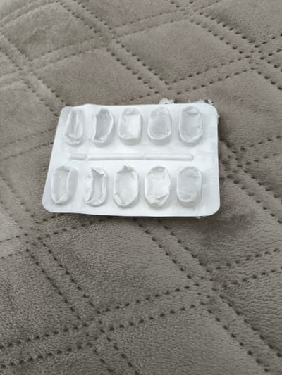 The image shows an empty blister pack of medication lying on a grey, quilted blanket. The blister pack contains 12 individual compartments, all of which are empty and show signs of use. The blanket has a diamond-shaped pattern of stitching. There are no people or other objects visible in the image. The location in the city of Marl, Germany is not specified or discernible from the image itself.