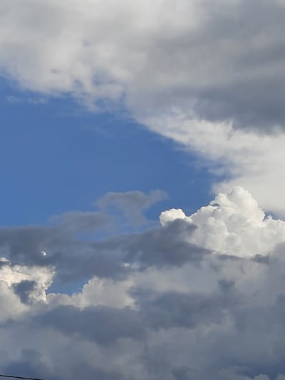 The image shows a sky filled with clouds, with patches of blue sky visible. The clouds are of varying densities and colors, ranging from bright white to dark gray. In the foreground, a dark horizontal line, possibly a wire or power line, is visible at the bottom of the frame. There are no people or recognizable landmarks to indicate a specific location within the city of Sluck, Belarus. The scene is entirely focused on the atmospheric conditions of the sky.