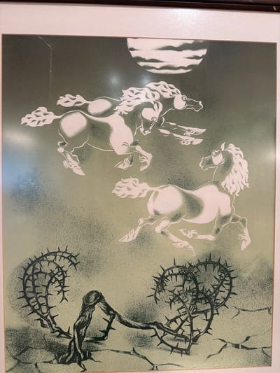 The image is a framed print featuring a stylized depiction of horses and thorny branches against a muted green, textured background. In the upper portion, three horses appear to be galloping across a cloudy, moonlit sky. The horses are rendered in white with dark outlines, suggesting a stencil or screen-printing technique. Their manes are flowing, and their bodies are muscular and dynamic.

In the lower portion of the print, two large, coiled masses of thorny branches are prominent. These branches are depicted in black and have sharp, prominent thorns. A gnarled, tree-like form connects the two thorny masses. The ground beneath the branches appears cracked and barren. The overall mood of the print is dramatic and somewhat unsettling, with a stark contrast between the ethereal horses and the menacing thorny elements.

This image is not located in Ankara, Turkey. It is a framed artwork, likely a print, and there are no indicators within the image itself to suggest a specific geographical location in Ankara or any other city.