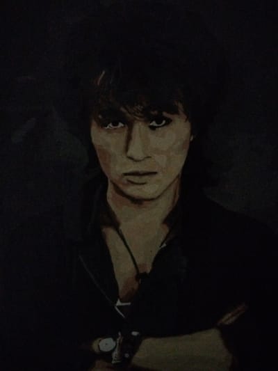 The image is a painting of a person, likely a man, with dark, tousled hair. The subject has striking eyes and a somewhat somber expression. They are wearing dark clothing, and their arms appear to be crossed. A watch is visible on the subject's left wrist. The background is dark and indistinct, creating a moody atmosphere. The painting is rendered in a somewhat impressionistic style, with visible brushstrokes. There is no indication of any specific location within the city of Novostroika, Russia, or any other geographical context.