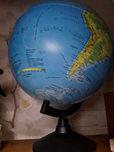 The image shows a globe of the world. The South American continent is prominently displayed. Parts of the globe are labeled in Russian. A depth chart is located on the bottom left of the globe in Russian. The globe is resting on a surface.
There is no evidence to suggest that the image was taken in the city of Amzya, Russia.